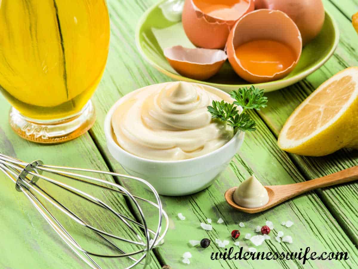 some of the ingredients for KitchenAid Mayonnaise recipe -egg yolks, oil, lemon - set on a wooden table.